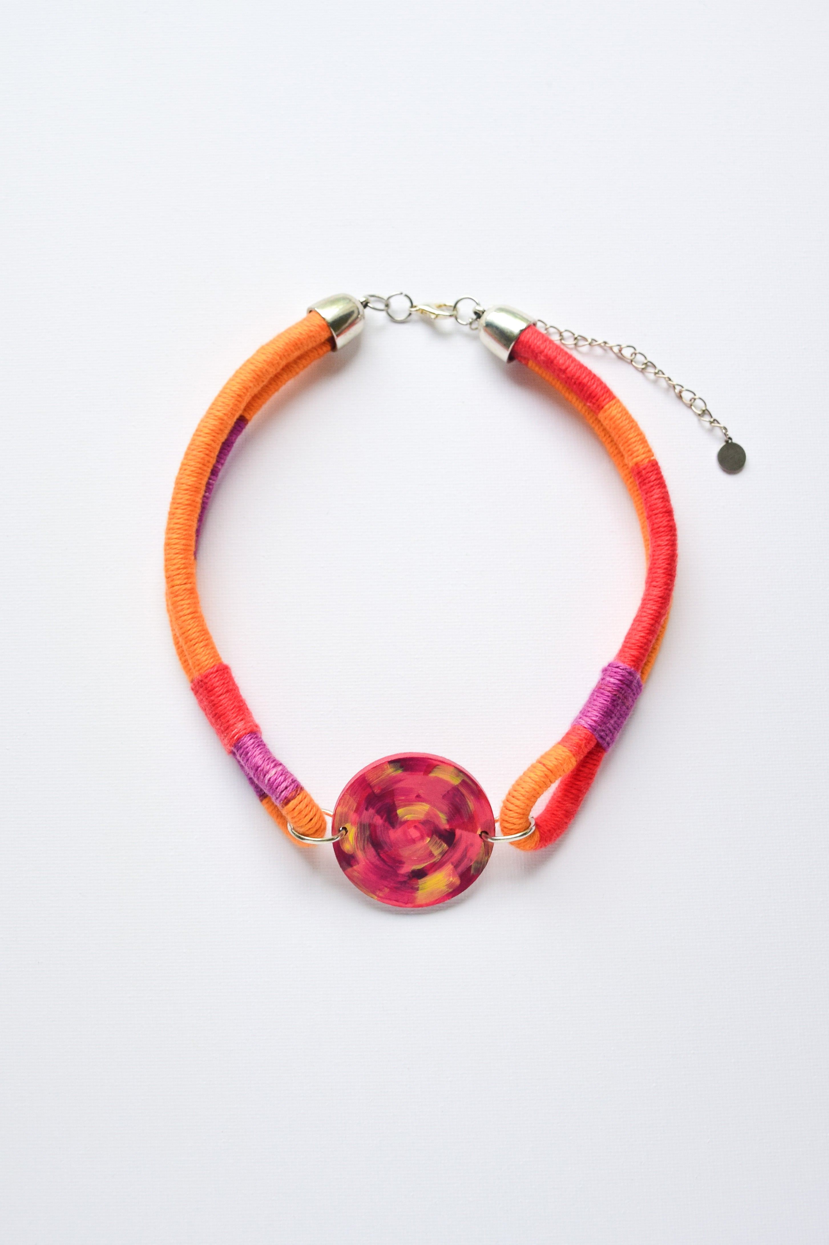 Necklace with colorful pendant in red, orange and violet tones on a white background