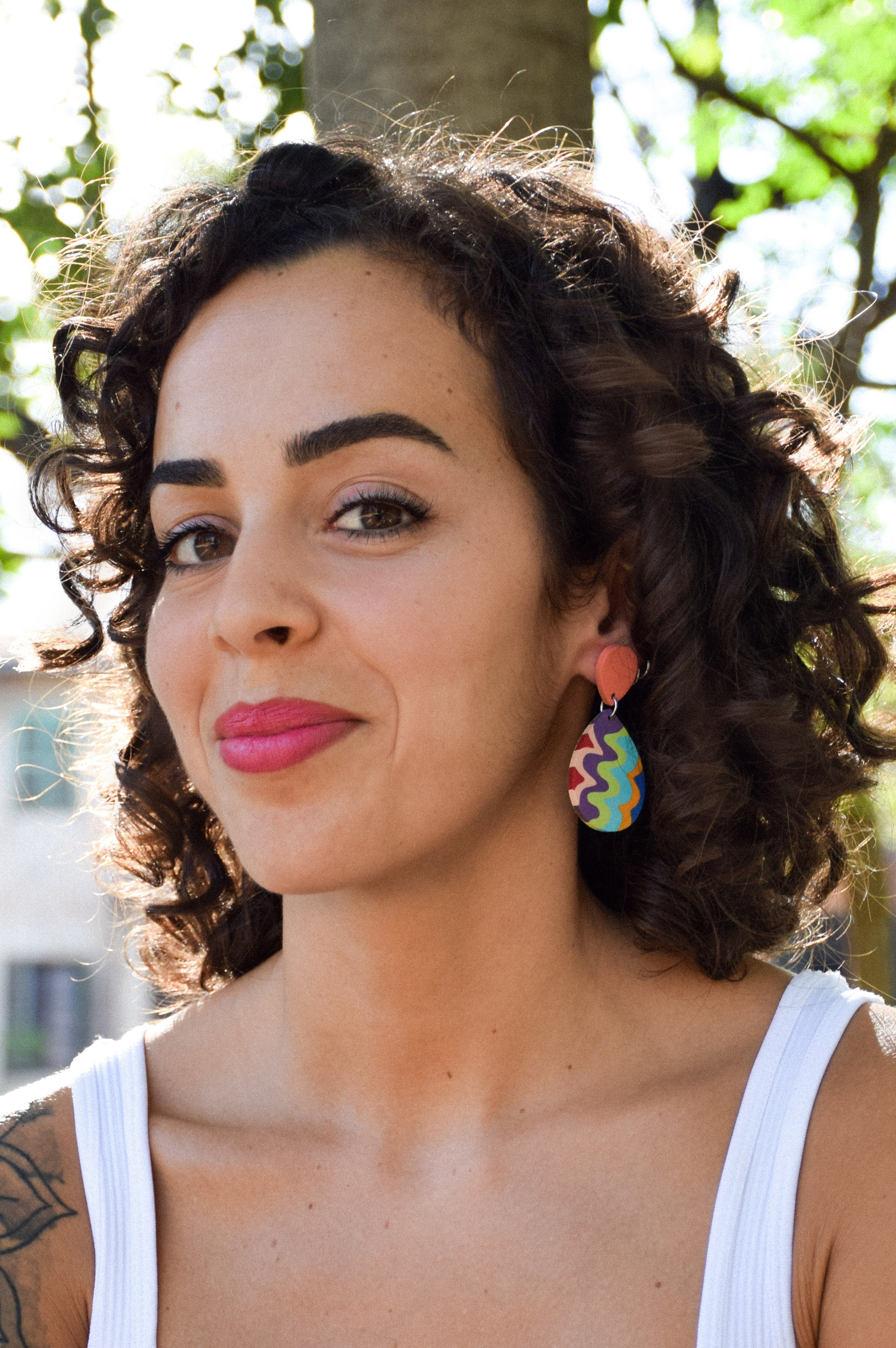 Woman with curly hair wearing colorful earrings outdoors