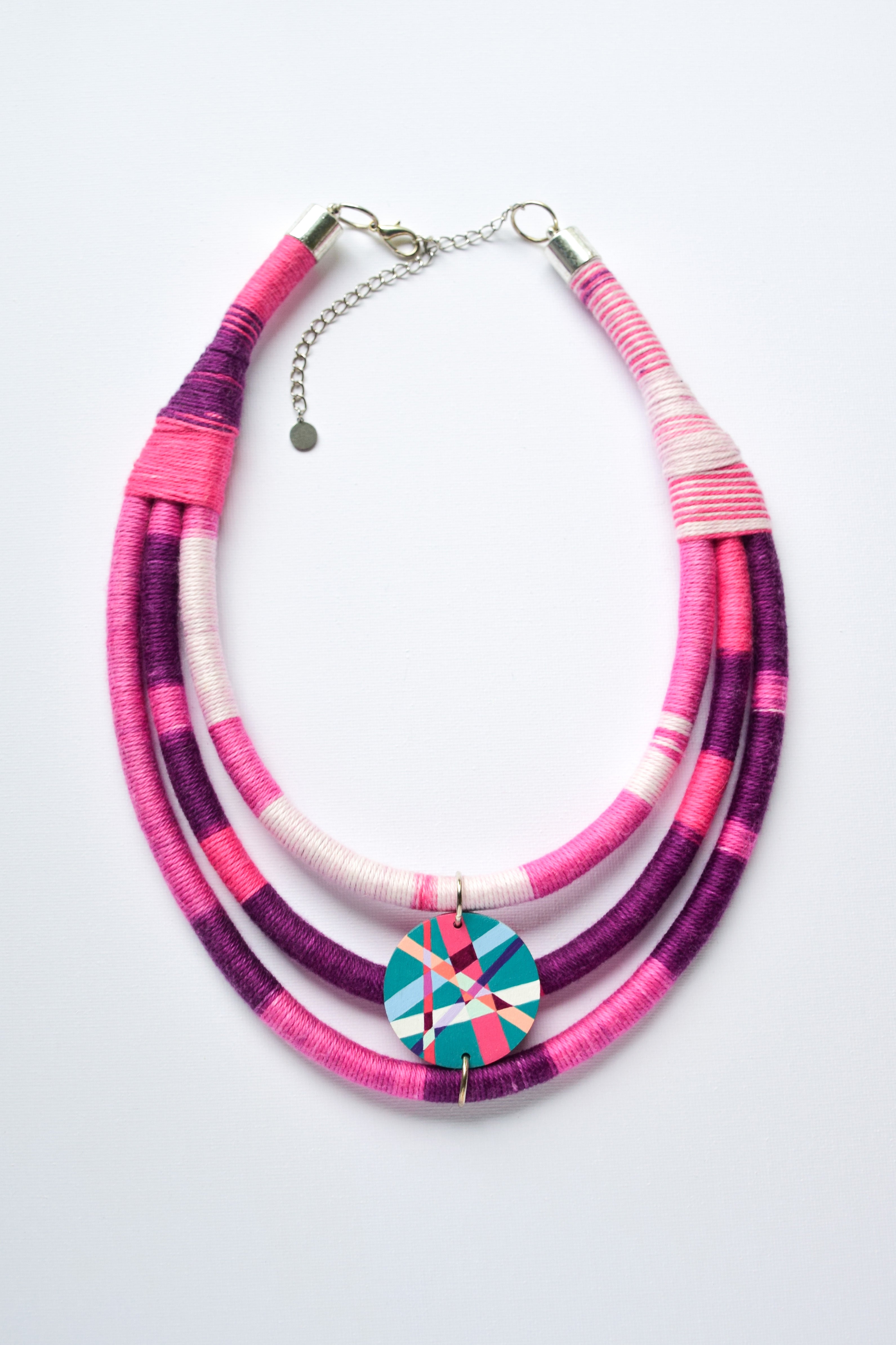 Necklace with pink and purple strands and hand-painted pendant on a white background