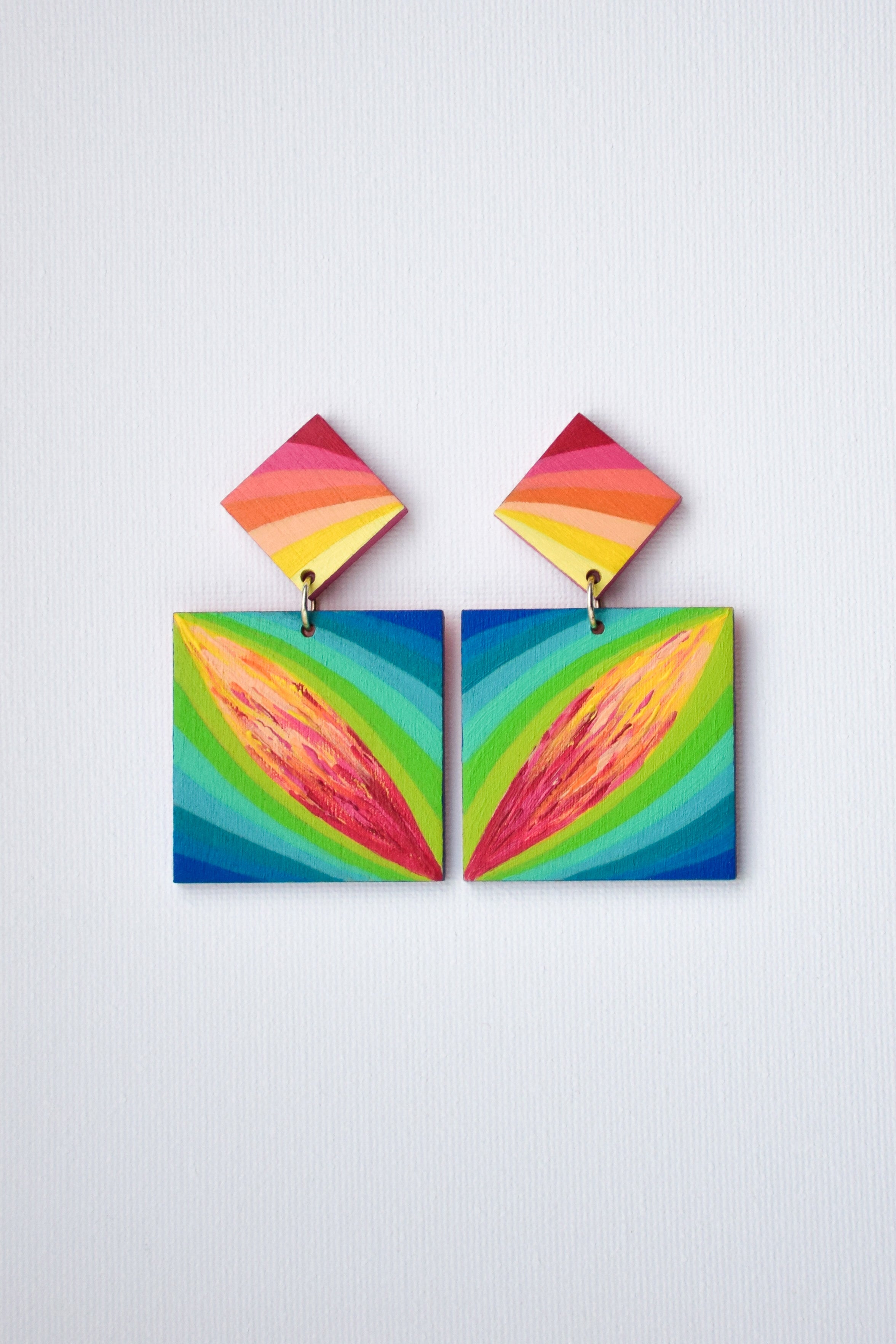 Colorful hand-painted geometric earrings on a light gray background