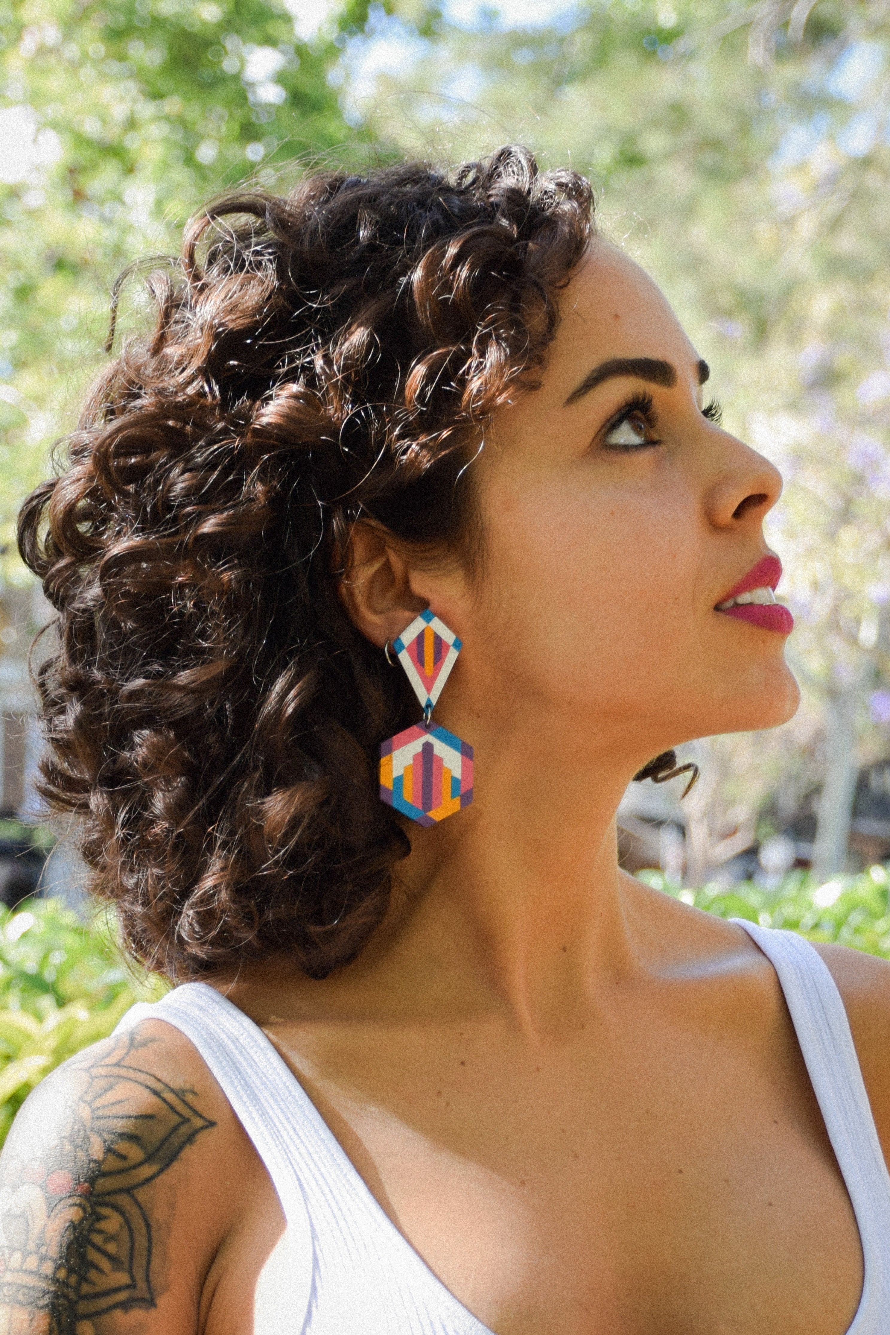 Woman with styled hair and colorful earrings outdoors