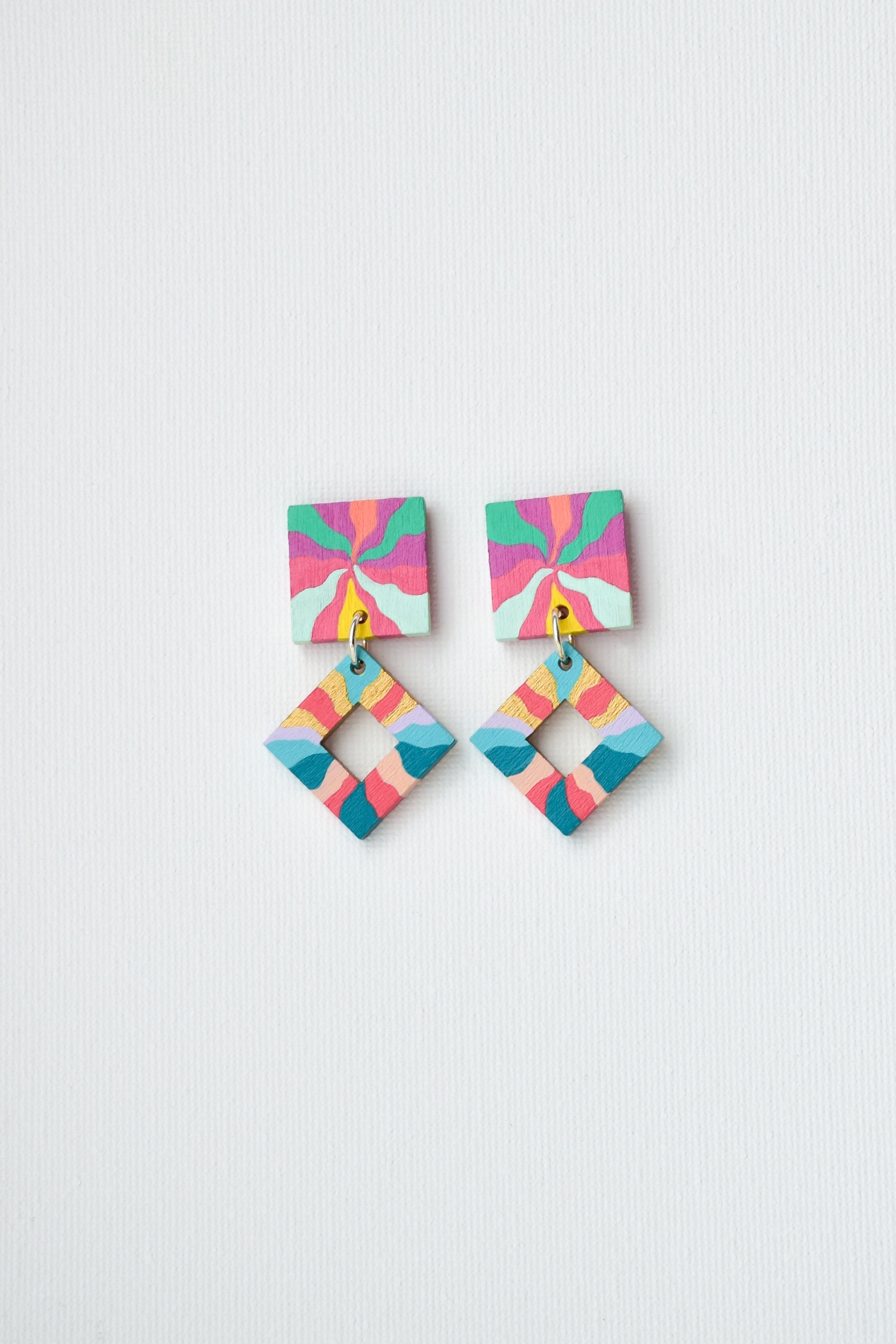 Colorful hand-painted geometric earrings on a light gray background