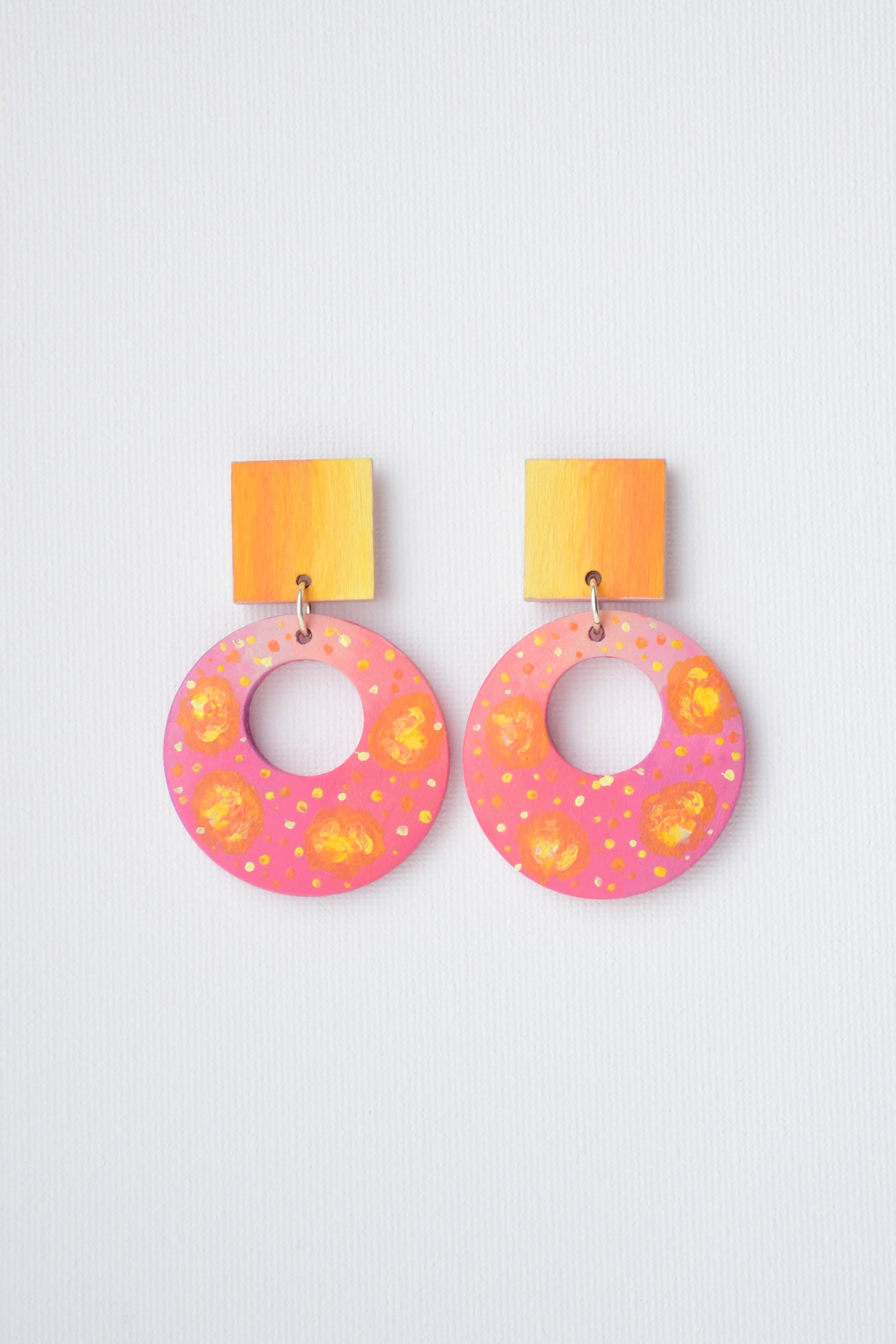 Pair of pink earrings with yellow accents on a light gray background