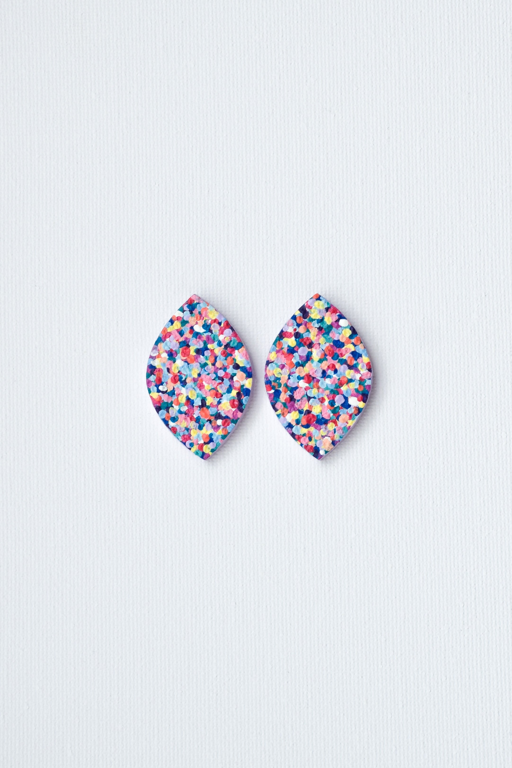 Multicolored speckled earrings on a light gray background