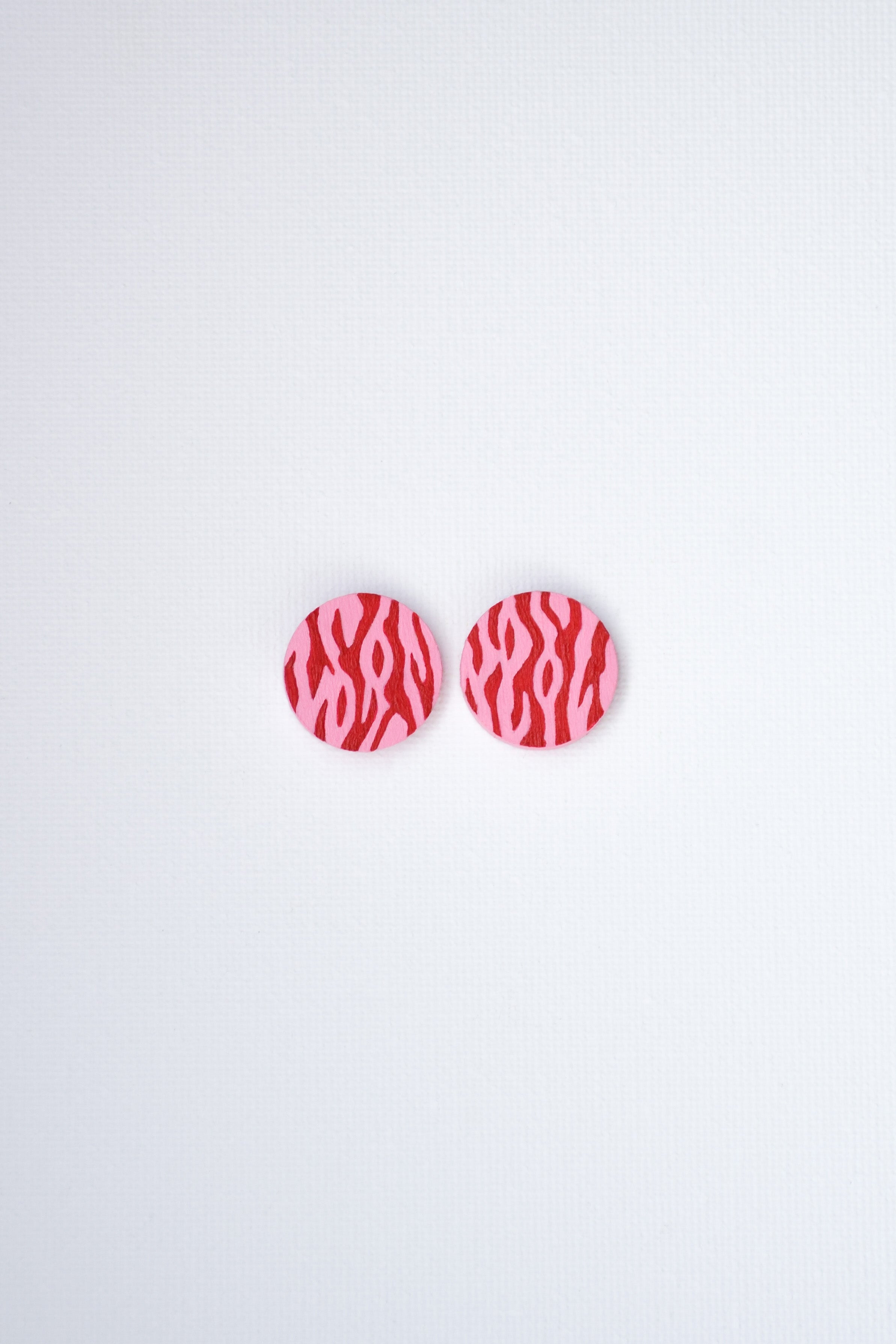 Pair of red and pink patterned earrings on a light gray background