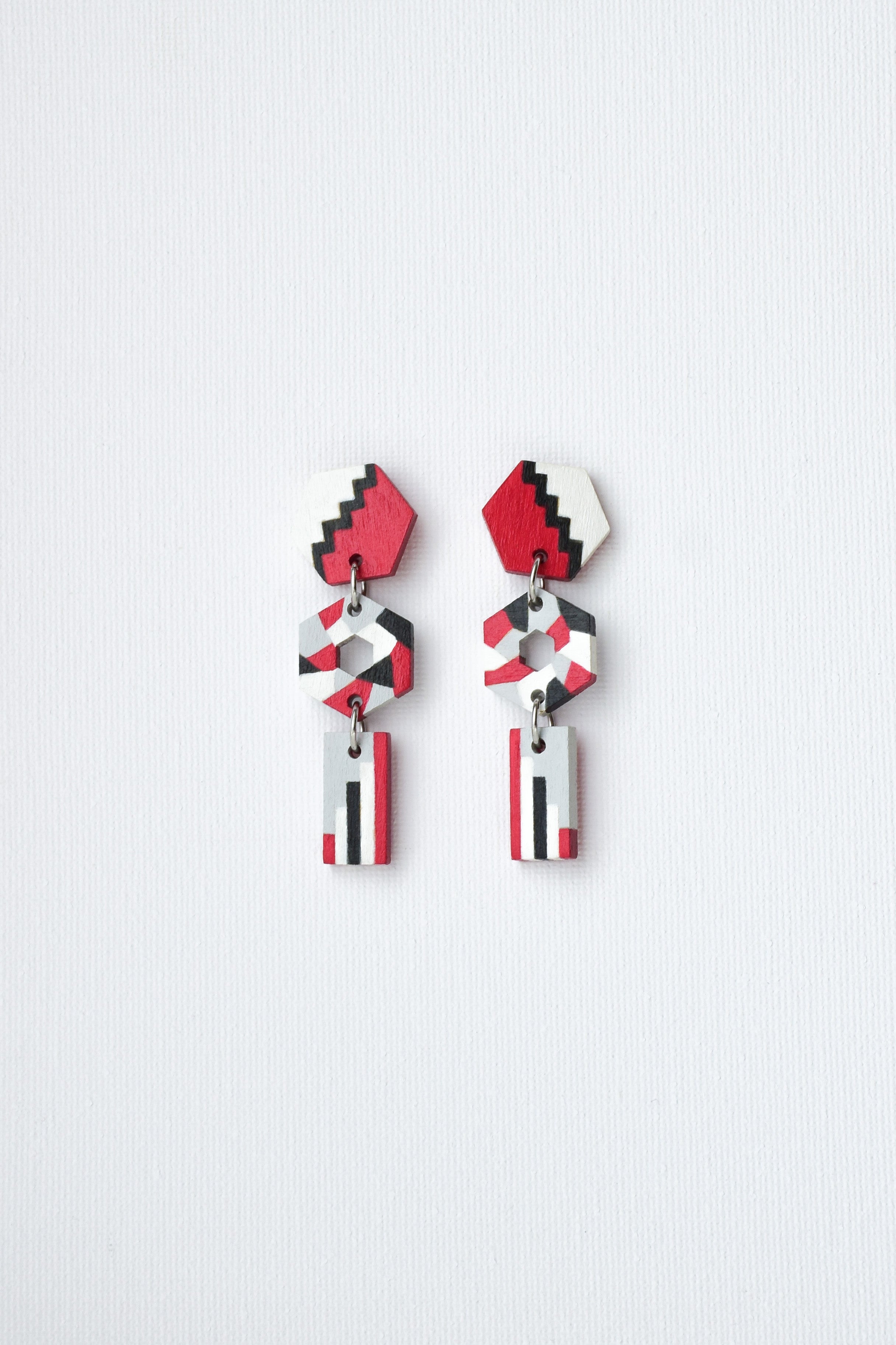 Pair of hand-painted geometric earrings on a light gray background