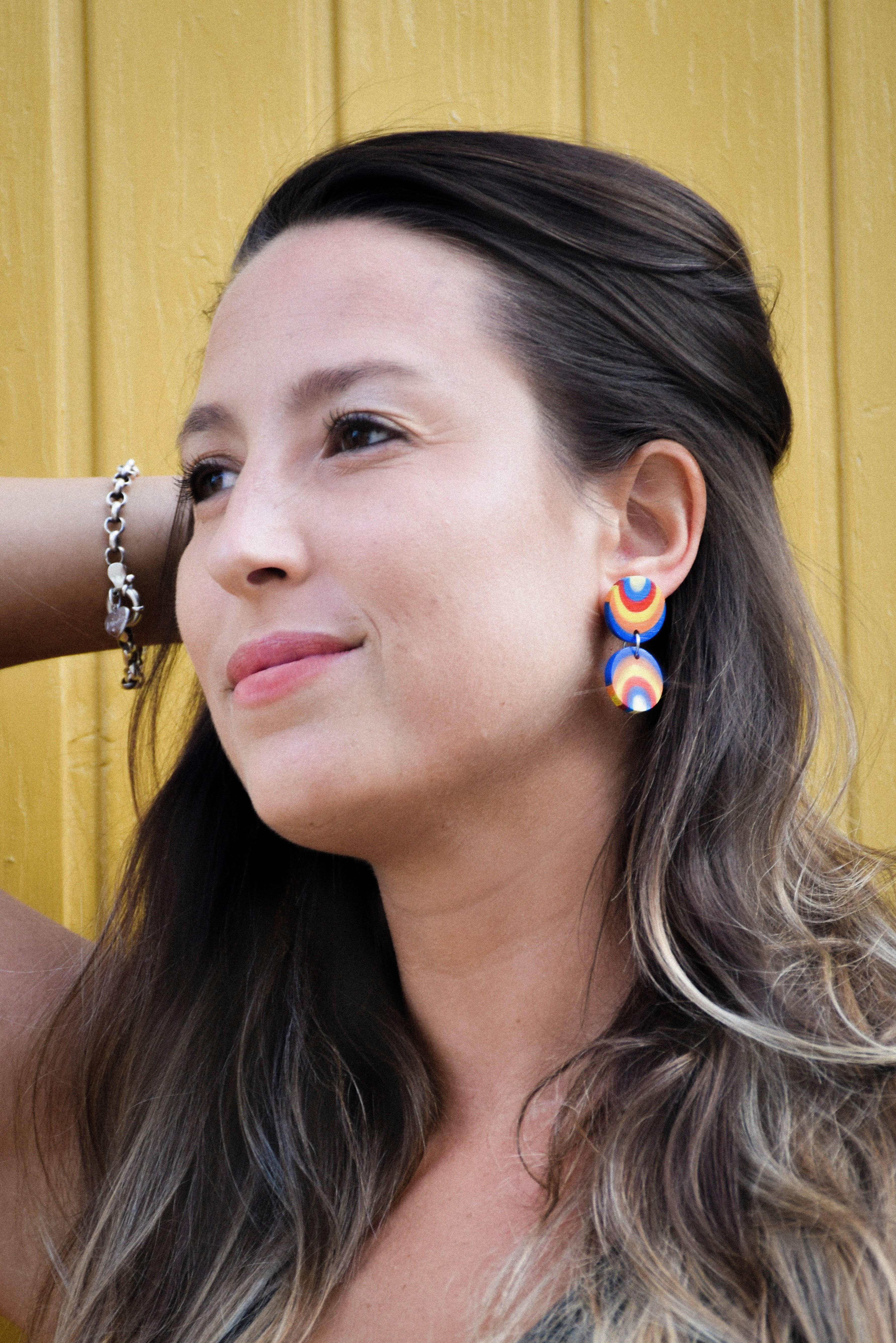 Woman wearing colorful earrings with a yellow background