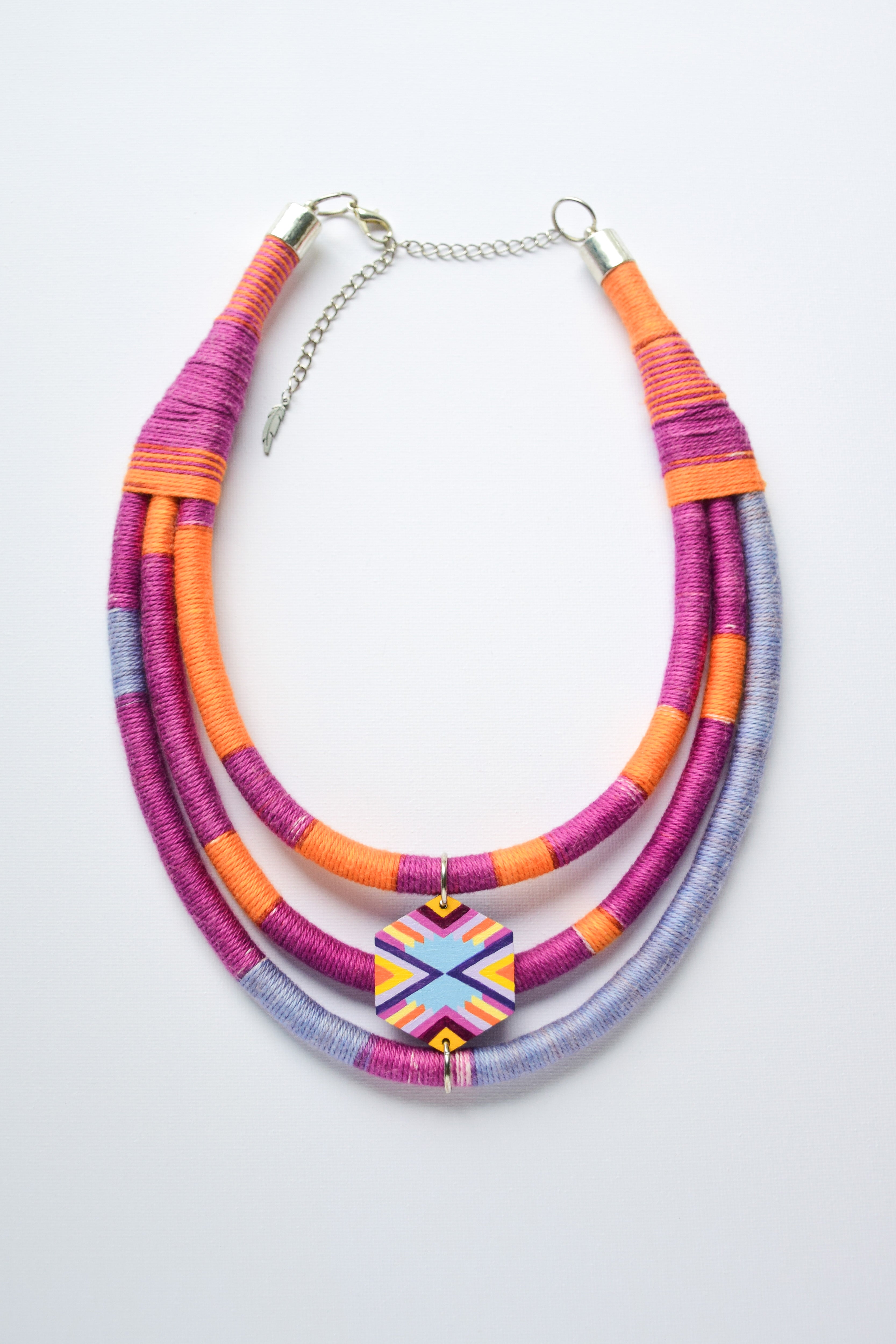 Colorful necklace with multiple strands and hand-painted pendant on a light gray background