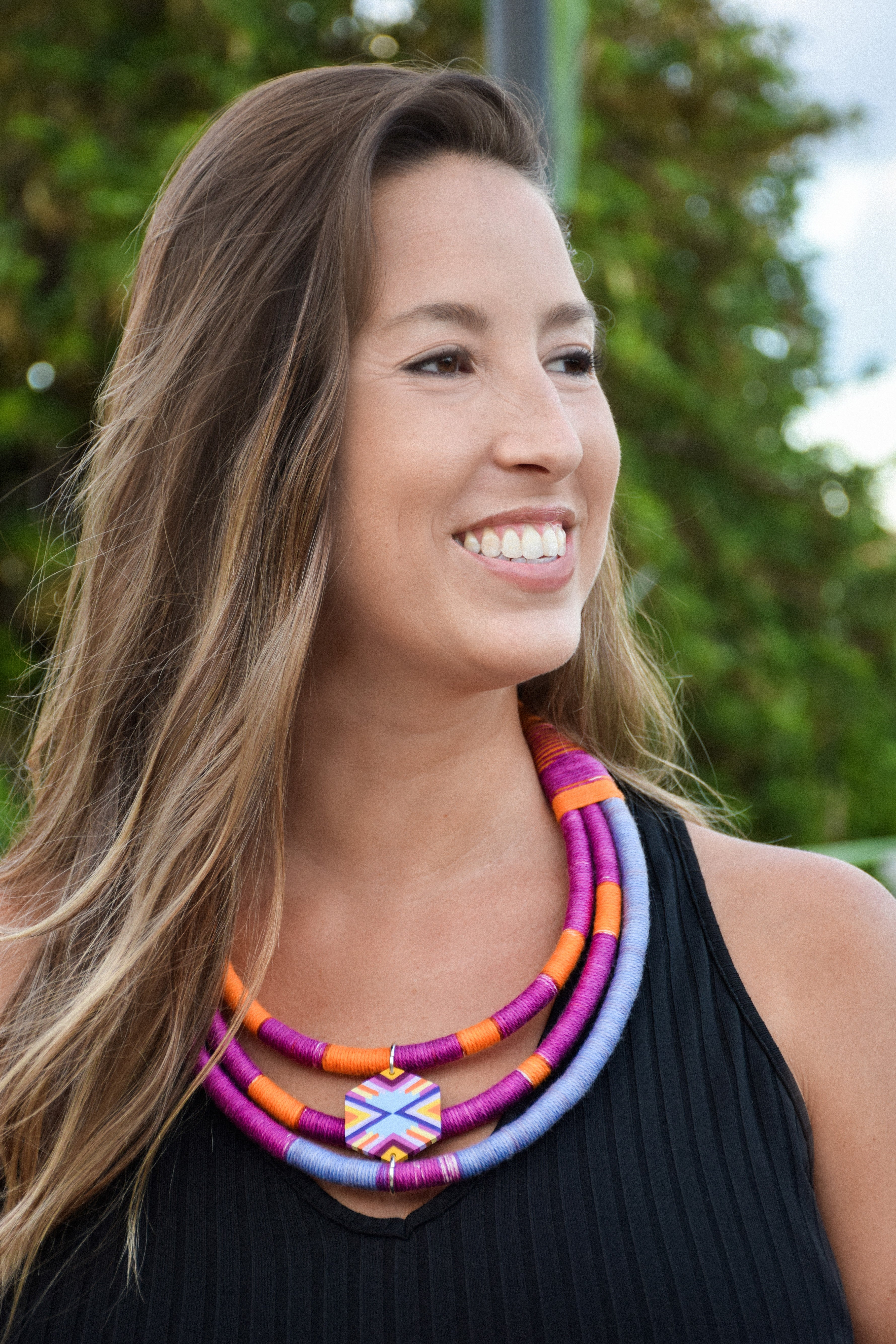 Woman wearing a colorful necklace with a blurred green background