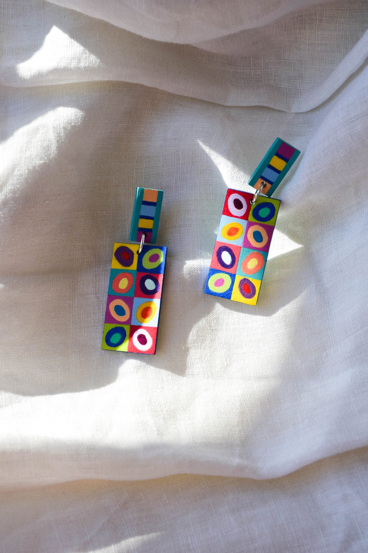 Colorful geometric earrings on a white fabric background
